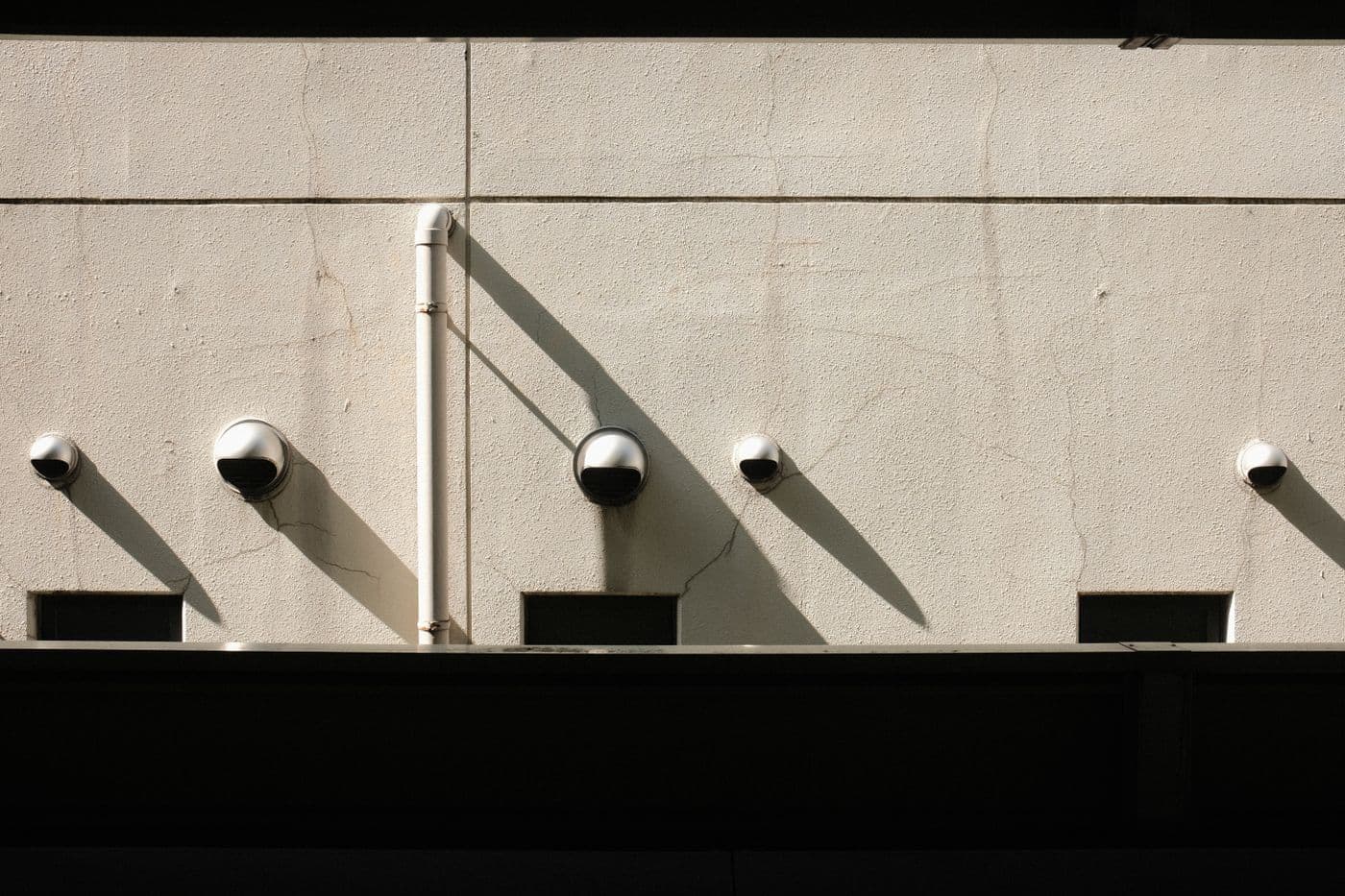 Plusieurs caméras dôme alignées sur un mur clair